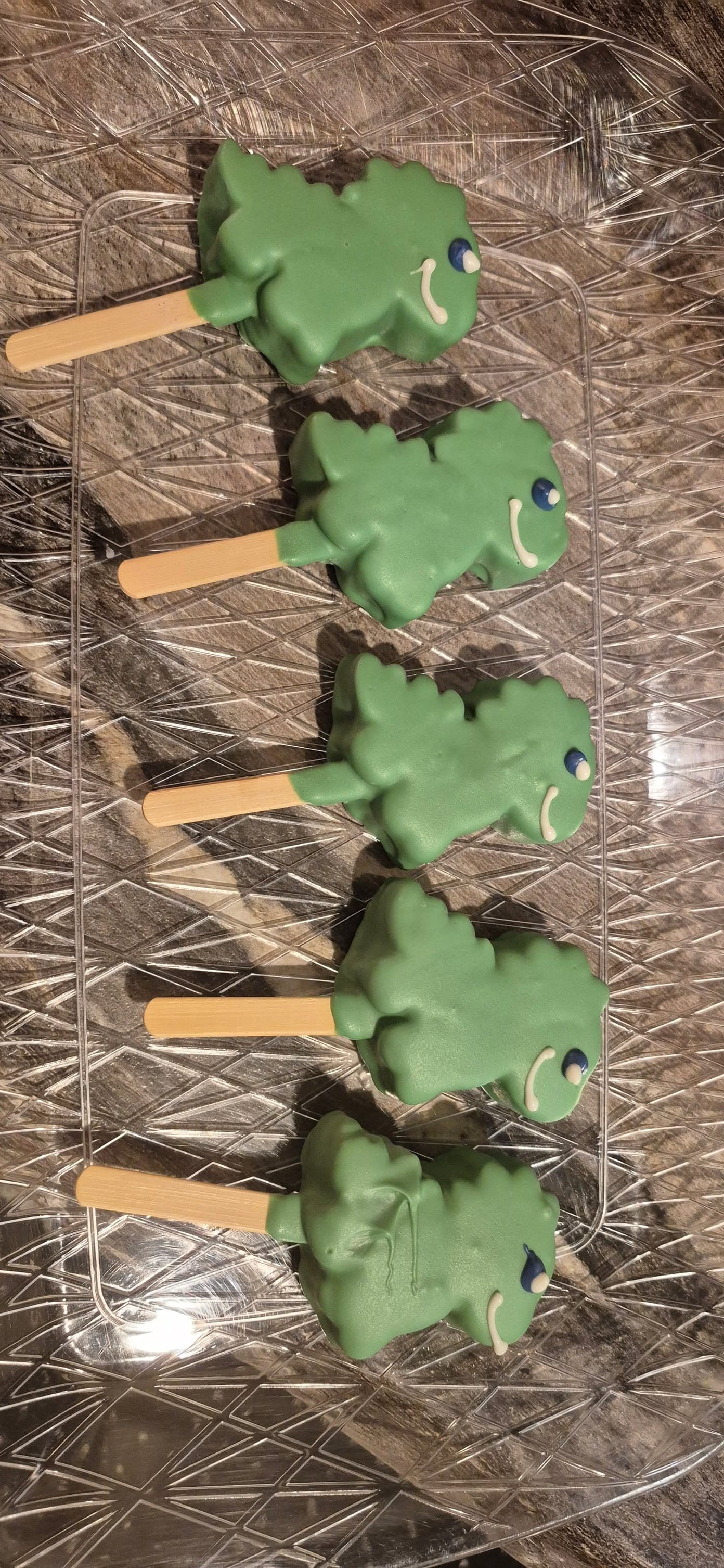 Green cake pops with dark chocolate drizzle on wooden sticks