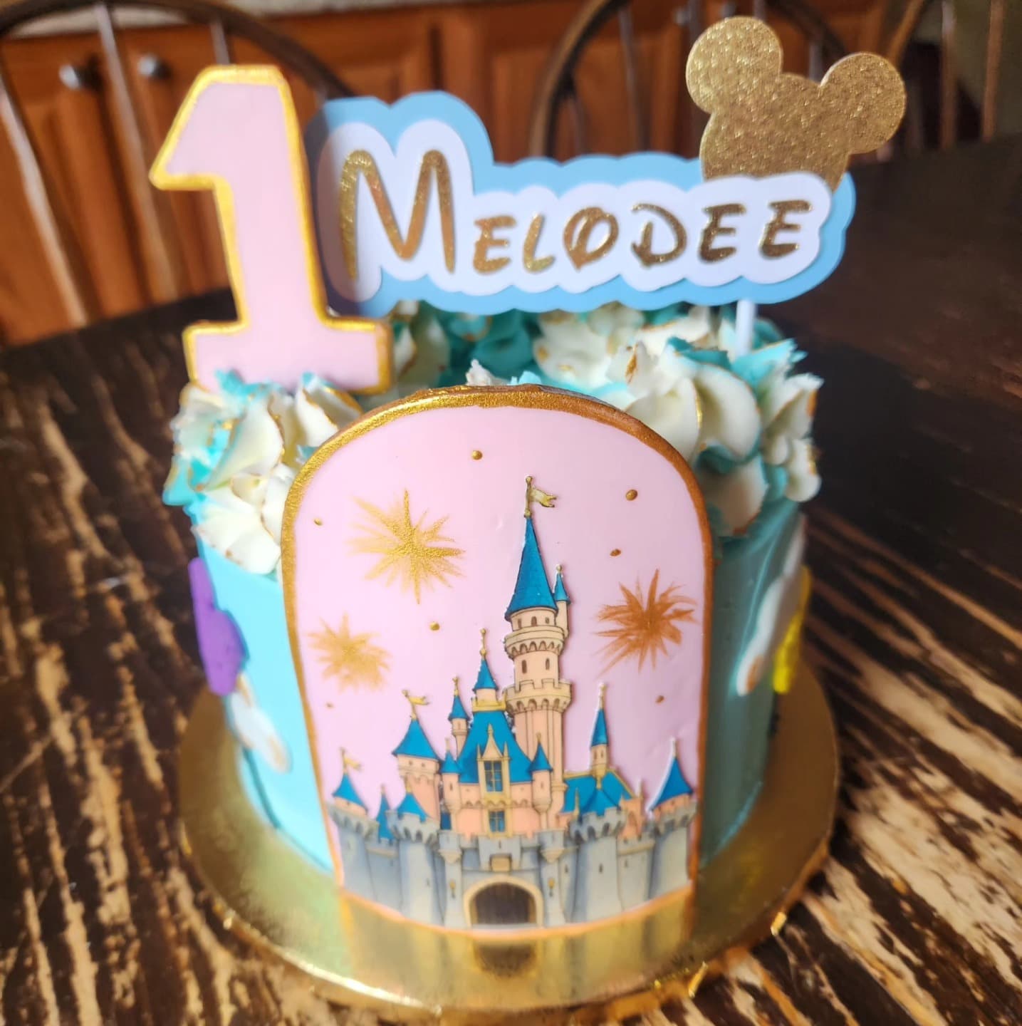 Castle-themed birthday cake with pink frosting and pastel flowers